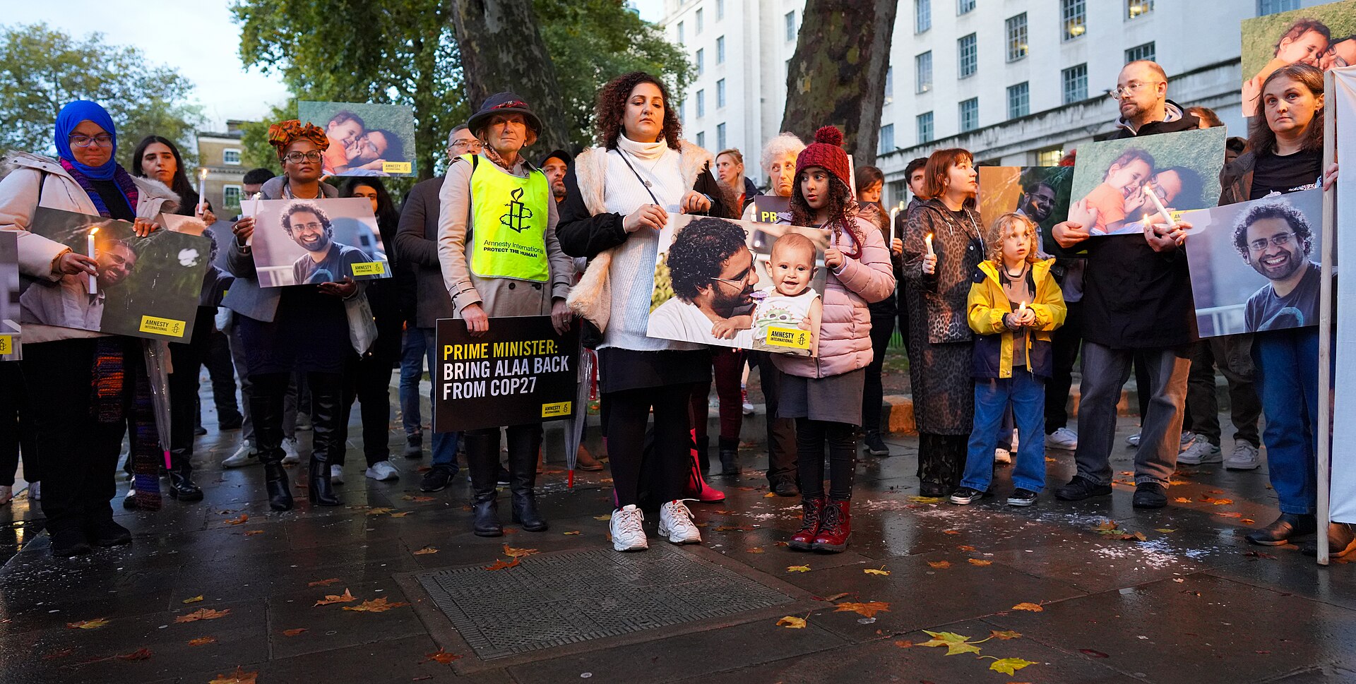 On Sunday 6 November, activists gathered outside Downing Street for a candle-lit vigil as British-Egyptian democracy dissident, Alaa Abd El-Fattah, escalated his hunger strike in an Egyptian prison, refusing to take water. في يوم الأحد 6 نوفمبر ، تجمع نشطاء خارج داونينج ستريت في وقفة احتجاجية أضاءتها الشموع ، حيث صعد المنشق البريطاني-المصري عن الديمقراطية ، علاء عبد الفتاح ، إضرابه عن الطعام في أحد السجون المصرية ، رافضًا شرب الماء Alaa's sister, Mona Seif, who had been camped outside the Foreign Office for over a week in a solidarity protest, is in a white jumper holding the Amnesty International placard showing a photograph of Alaa with his son. His other sister, Sanaa Seif, was flying out to Sharm El Sheikh in a brave and risky effort to save Alaa. Even prior to his refusal of water from Saturday 6 November, Alaa was already over 200 days into his 100 calorie a day hunger strike in prison in Egypt. For the latest on Alaa's situation listen to his sister's Sanaa Seif's speech to journalists on Tuesday 8 November - at COP27 - "They are very happy for him to die. The only thing they care about is that it doesn't happen while the world is watching." www.youtube.com/watch?v=BqXibJ7PUTY Alaa Abd El-Fattah has endured much of the last twelve years in some of the worst prison conditions anywhere in the world, on account of his brave work in promoting democracy in Egypt. He was last arrested in September 2019 while attending Cairo's Dokki Police Station and in December last year was sentenced to five years imprisonment for "spreading false news undermining state security." More precisely, he had shared social media posts explaining the hell-hole reality of Egyptian prison conditions. TORA PRISON - "A DAY HERE, IS LIKE A YEAR IN BELMARSH" In April, Alaa began his hunger strike in a cell in one of the most secure sections of Cairo's sprawling and notorious Tora Prison - a maze of grim high concrete walls and watch towers, which strike fear into even the thousands of commuters who have to pass daily. In 2012, one young Londoner confined to one of the least uncomfortable and most survivable wings of Tora prison, contrasted it with his own previous experience at Britain's high security Belmarsh. I can never forget his exact words. "A day here, is like a year at Belmarsh!" A little over 12 months later, he died of TB - the prison authorities had refused to listen to the pleas of his aunt, who fell on her knees during a rare visit, begging that he be admitted to the prison hospital. ALAA'S HUNGER STRIKE CONTINUES AT WADI EL NATRUN PRISON More than 200 days have passed since Alaa started his hunger strike. He has now been moved to the Wadi El Natrun prison complex in the desert north of Cairo, dubbed by inmates as the "Valley of Hell." He may not survive much longer. However, as he holds British-Egyptian nationality, one would hope that the British government would be doing everything they could to secure his immediate release and it would be reasonable to suppose that the Foreign Office could get an immediate pledge in this regard, especially given that the British companies, including the likes of British Petroleum and BP, are the biggest investors in Egypt. NO CONSULAR ACCESS However, the British government have failed even to get him any consular access - think about that. That's an outrage. Even a convicted mass murderer, if British, would be entitled to consular access while in prison. That meeting would obviously not take place in his cell - but in a designated room in the prison or the highly supervised prison visiting area. British men and women convicted of drug smuggling and other crimes in Egypt have received consular visits, so why not Alaa? The answer is because Alaa's crime is that he dared to tell the truth about Egypt, and the injustice both inside and outside its many prison walls. Nobody knows exactly how many political prisoners Egypt now has, but the number is estimated to be at least 60,000. ALAA WAS ONE OF THE LEADERS OF THE MOST INSPIRATIONAL DEMOCRATIC REVOLT THE WORLD HAS EVER SEEN Alaa Abd El-Fattah was one of the leaders of arguably the most inspirational democratic revolt the world has seen in the last hundred years. Although the first phase of the 2011 uprising in Egypt lasted just 18 days, and although it followed the toppling of the dictator Ben Ali in Tunisia - the streets and bridges around Tahrir Square became a deadly stage watched by the world, where protesters from every walk of life were pitted against Egypt's feared state security forces. Against all the odds, and at the cost of many lives, Egyptians refused to leave the square, sleeping in front of the tanks and fending off attacks from government militia. The Egyptian people's initial success in toppling the dictator Mubarak led to further revolts not just across the Middle East (most notably in Libya, Bahrain, Yemen and Syria) - the highly organised Tahrir-Square sit-in provided the inspiration for strikes and workplace sit-ins against austerity across the United States and Europe and to the Occupy Movement of the same year. The people of Egypt showed that it does not matter how brutal, feared and authoritarian a government is, it can be toppled if people act collectively. THE MILITARY BACKLASH It's true that Egypt's flirtation with the path to greater freedom seemed to be only temporary - the Egyptian authorities deployed the usual divide and rule tactics - encouraging the less committed protesters to return home - and then rushed to elections without allowing time for genuinely democratic opposition parties to develop. Mohamed Morsi of the Muslim Brotherhood won the presidential election in 2012 - the Brotherhood (contrary to the perception many people have here in the West) had genuinely progressive elements within it, but the chance for any transformative radical programme was prevented partly by the corruption and self-interest of some of the main political actors and partly by opposition to its democratic mandate from the deep state (the military, the Interior Ministry, State Security, the police etc.) The army, seeing its chance, seized power in 2013, superficially in the name of the people, but in reality, to advance the interests of the generals. The new president, Abdel Fattah El-Sissi, moved quickly to crush all opposition, and ordering his security forces to attack Muslim Brotherhood supporters who had gathered in eastern Cairo at Rabaa al-Adaweya Square, killing at least 800 people - the bloodiest massacre of civilians in Egypt's modern history. DON'T ALLOW EGYPT TO USE COP27 TO GREENWASH ITS REGIME - AND PLEASE SIGN THE PETITION TO SAVE ALAA Now COP27 is scheduled to take place in Sharm El-Sheikh and Sisi has been given a golden opportunity to greenwash his murderous regime, which has also seen ever increasing levels inequality and corruption. While British representatives at COP27 will be given accommodation in the most luxurious five star hotels in Sharm El-Sheikh and fall asleep listening to the sound of the waves, another British citizen, Alaa Abdel El-Fatah is near death, on a painful hunger strike in the darkest of places - his dimly lit cell. The only thing he might hear at night is the desperate cry from some prisoner in another cell appealing for medical help which most likely never comes. If we care for freedom, real democracy and justice, we can't allow the British Foreign Office to forget Alaa - especially if it's simply not to upset the highly profitable relationship British multinationals have with one of the world's most authoritarian and corrupt regimes - a relationship which only benefits the wealthiest of Egyptians. Please show your support by signing the petition. Let's not fail Alaa. Thank you. www.change.org/p/help-free-my-brother-before-it-s-too-lat...